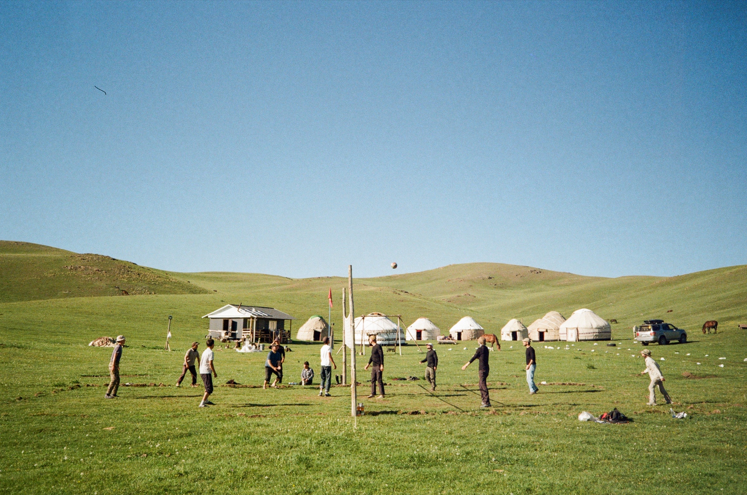 Travellers playing volleyball beside yurts on the grasslands of Song-Köl, Kyrgyzstan - Travel photography by Rocco Goldschmidt