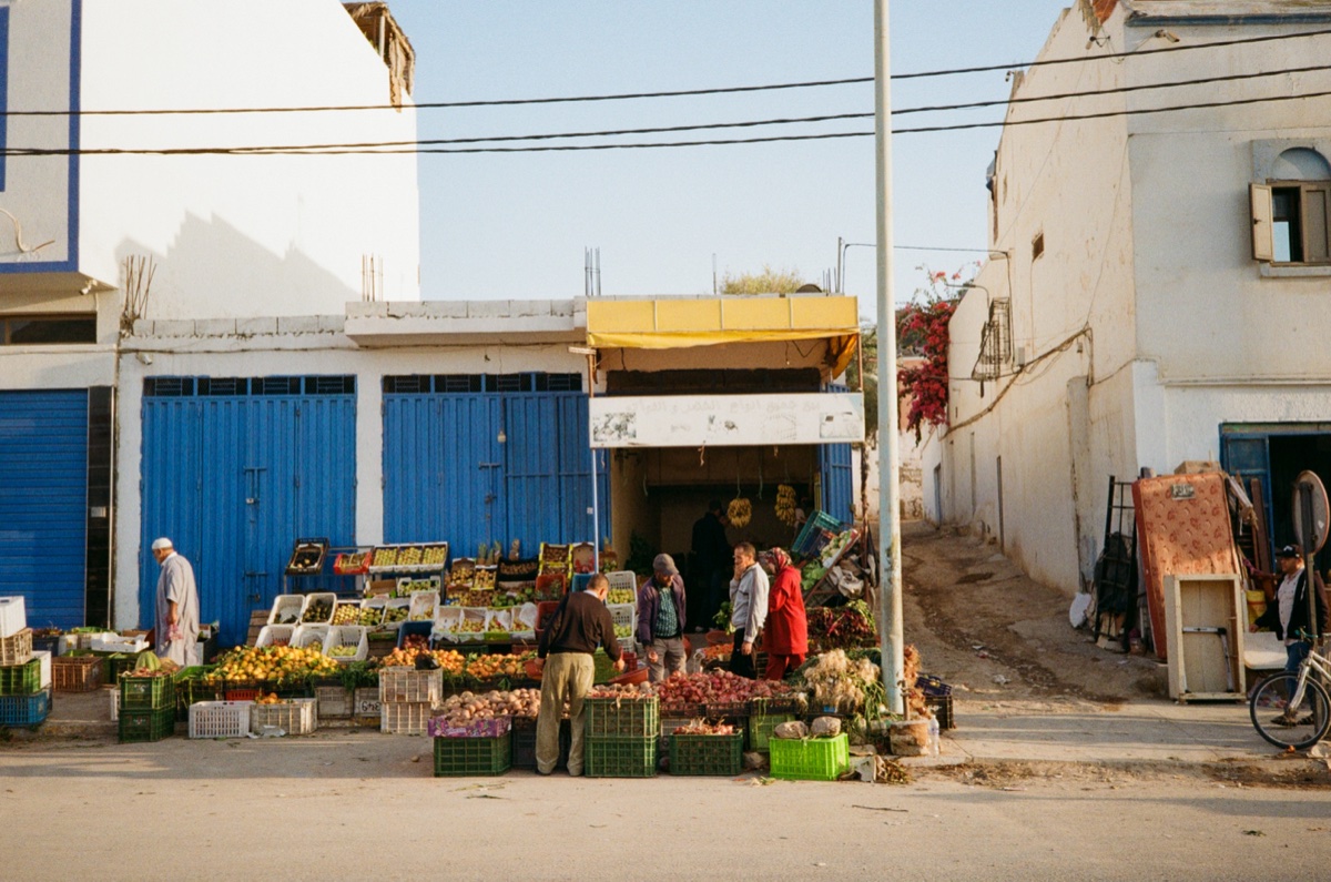 Camel handler and man in blue djellaba on the beach in Aourir, Morocco - Street photography by Rocco Goldschmidt