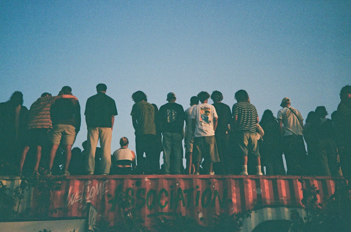 Fruit and vegetable market stall with blue doors and people shopping in Taghazout, Morocco - Street photography by Rocco Goldschmidt