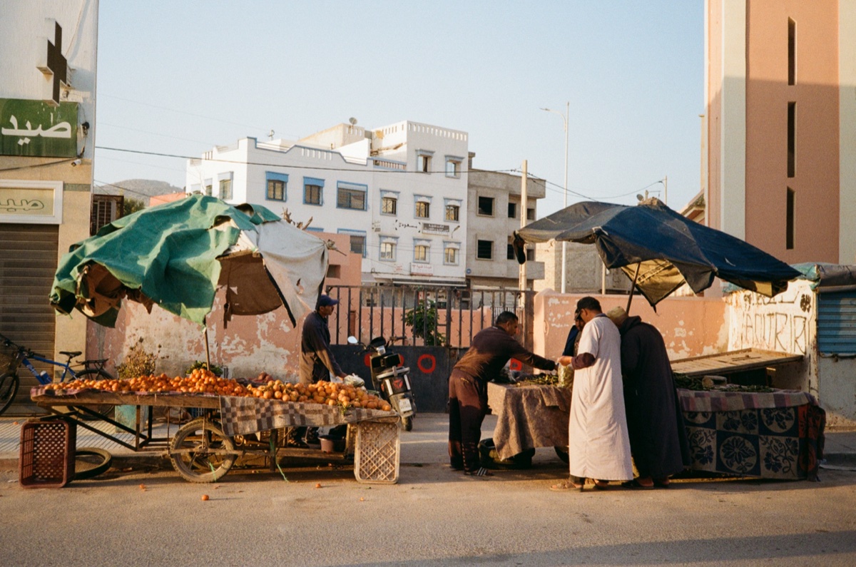 Crowd standing on a wall at dusk with Welcome Association graffiti in Aourir, Morocco - Street photography by Rocco Goldschmidt