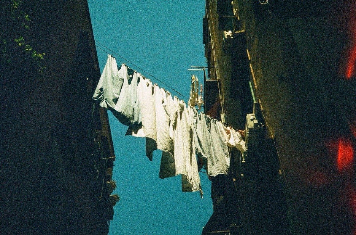 White laundry hanging across a narrow alley against blue sky in Napoli, Italy - Street photography by Rocco Goldschmidt