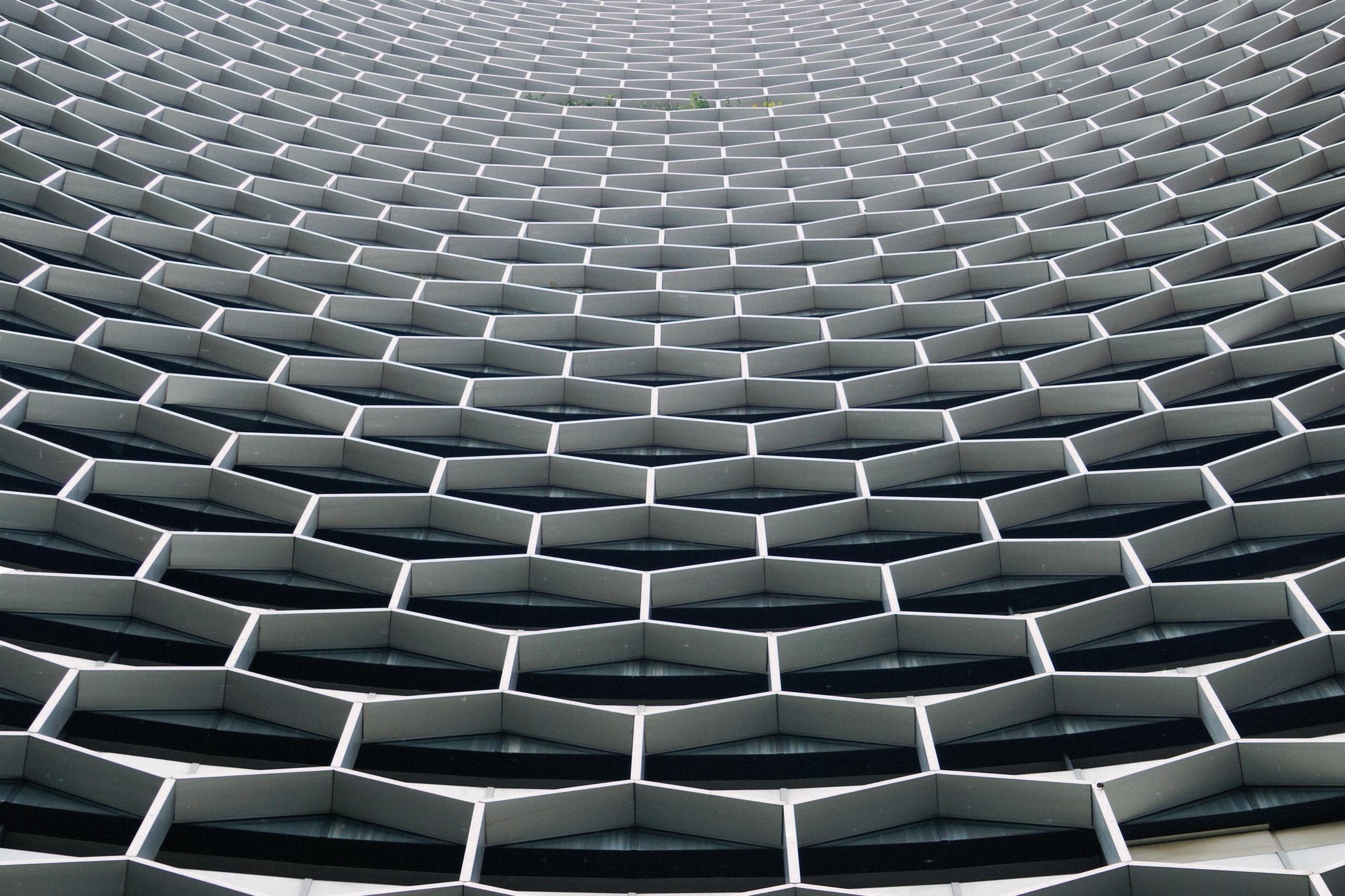 Curving honeycomb pattern of hexagonal window frames on a building facade in Singapore - Architecture photography by Rocco Goldschmidt